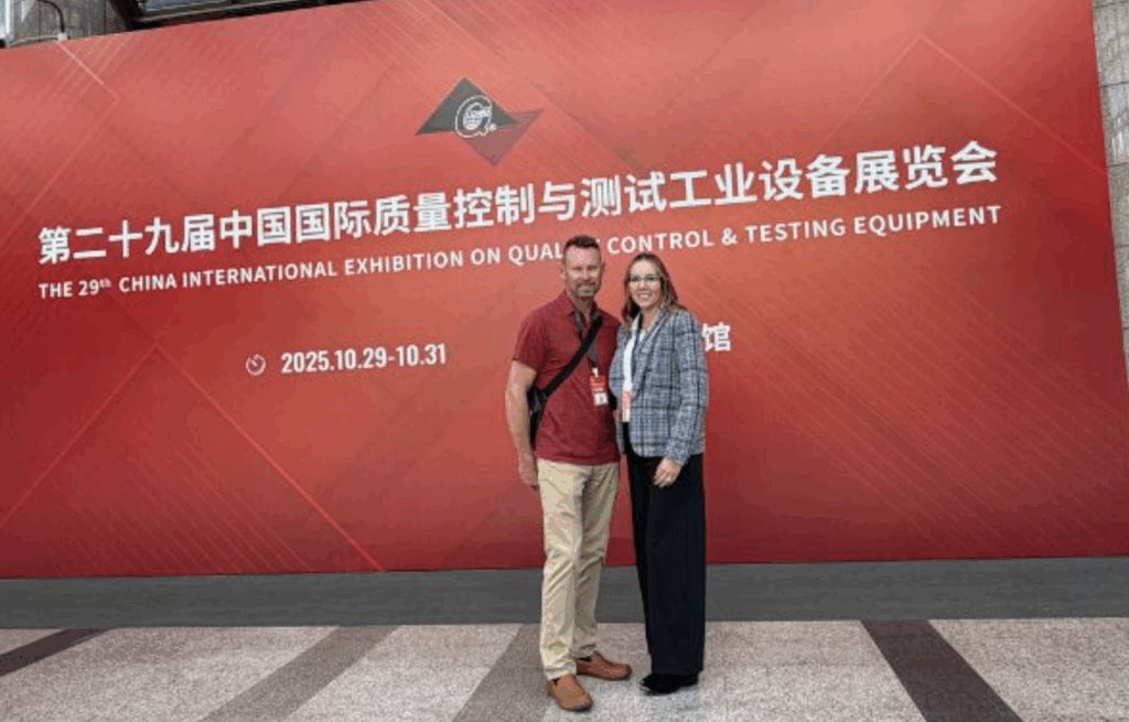 IFE NDT Executives, Michael and Jamie Clemons, standing in front of the QC Expo Sign